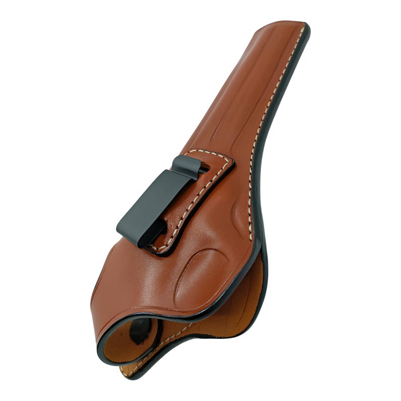 Op de afbeelding: Een bruin leren holster met een zwarte metalen clip. De holster heeft decoratieve stiksels en een gevormd ontwerp. De randen zijn zwart en de binnenkant is lichtbruin. Ontworpen om een vuurwapen te bevatten.