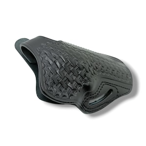 Pode incluir: Coldre de couro preto com um padr&atilde;o de tecido de cesta. O coldre foi projetado para segurar uma arma de fogo e apresenta uma forma moldada com detalhes de costura. O couro &eacute; de cor preta profunda.