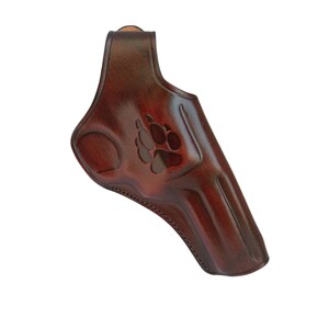 K&ouml;nnte beinhalten: Ein braunes Lederholster mit einem Pfotenabdruck-Design.