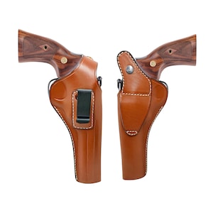 May include: Two brown leather holsters with white stitching and black belt clips. The holsters are designed to hold a handgun. The grips of the handguns are made of wood with a dark grain pattern.