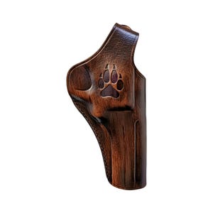 Peut inclure: Un &eacute;tui en cuir marron avec un motif de patte d'animal. L'&eacute;tui est en cuir marron fonc&eacute; avec une empreinte de patte marron clair en relief sur le devant. Con&ccedil;u pour contenir une arme &agrave; feu.