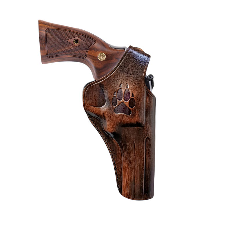 Peut inclure: Un &eacute;tui en cuir marron avec un motif de patte d'ours sculpt&eacute;, contenant un revolver avec une poign&eacute;e en bois. Le revolver a une finition en bois fonc&eacute; et un embl&egrave;me dor&eacute;. L'&eacute;tui est con&ccedil;u pour s'adapter au revolver en toute s&eacute;curit&eacute;.