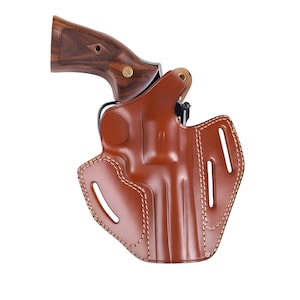 Può includere: Una fondina in pelle marrone con un revolver. La fondina presenta cuciture decorative e fessure ritagliate. Il revolver ha un'impugnatura in legno e un telaio in metallo. L'immagine è su sfondo bianco.