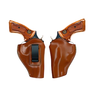 Può includere: Due revolver con impugnature in legno e fondine in pelle marrone. Le fondine hanno una clip da cintura nera. I revolver sono su sfondo bianco.