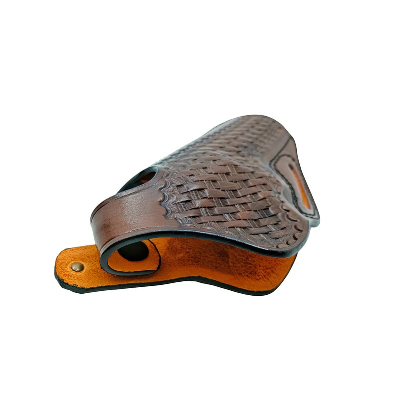 May include: A brown leather holster with a basketweave pattern. The holster has a curved shape with a loop and a snap closure. The interior is a lighter shade of brown.