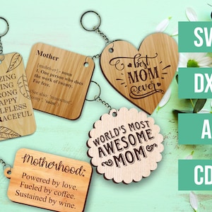 Op de afbeelding: Houten sleutelhangers met verschillende gegraveerde berichten voor Moederdag. Ontwerpen omvatten "Beste mama ooit", "'s Werelds meest geweldige moeder" en definities en inspirerende woorden.