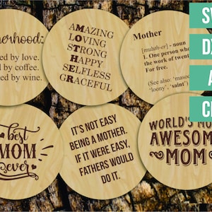 Puede incluir: Conjunto de seis posavasos redondos de madera con diferentes frases sobre la maternidad. Los posavasos presentan texto marrón sobre un fondo de madera claro.