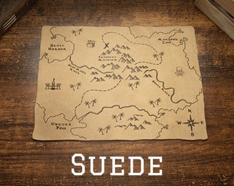 May include: A brown leather map with a pirate theme. The map features a compass, mountains, a skull and crossbones, and the text "Treasure Mountain", "Skull Harbor", "Dead Man's River", "Morgan's Cove", "Unicorn Pass", and "Shark River". The map is labeled "SUEDE" at the bottom.