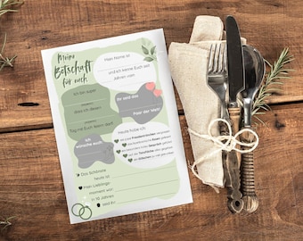 May include: A wedding-themed stationery set with a decorative design, featuring a fill-in-the-blanks card and a napkin with silverware tied with twine. The card has text in German. The items are arranged on a wooden surface.