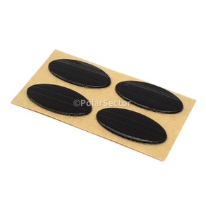 May include: Four black oval-shaped adhesive pads on a brown paper backing.