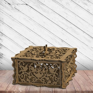 Könnte beinhalten: Eine Holzkiste mit filigranen Ausschnitten von Vögeln und Blumen. Die Kiste ist aus hellbraunem Holz gefertigt und hat ein zartes, verziertes Design.