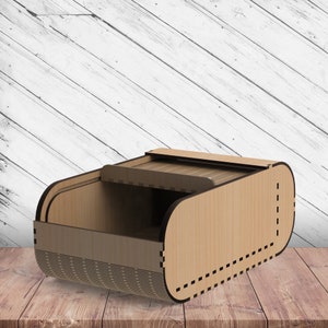 May include: A wooden box with a sliding lid. The box is made of light brown wood and has a decorative pattern on the front.