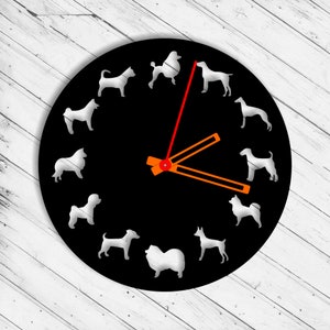 Puede incluir: Cara de reloj negra con siluetas de perros blancas alrededor del borde. Las manecillas del reloj son naranja y rojo.