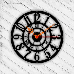 May include: Black metal clock with Roman numeral markings and an intricate design. The clock face has a black background with white Roman numerals and a black and white design in the centre. The clock hands are red and orange.