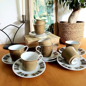 May include: Set of six brown ceramic coffee cups with matching saucers. Each saucer features a geometric pattern in shades of brown, green, and white.