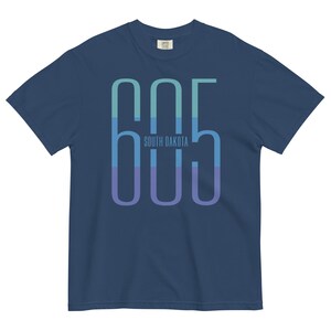 May include: A navy blue t-shirt with a graphic of the number 605 in a gradient of blue and green colors. The text "SOUTH DAKOTA" is printed below the number.