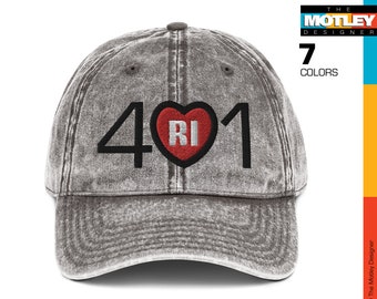 Puede incluir: Una gorra de béisbol gris desgastada con un diseño bordado en negro que dice "401" con un corazón rojo que contiene las letras "RI" en el centro.