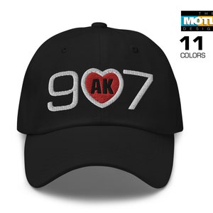 May include: Black baseball cap with white embroidered text "907" and a red heart with white "AK" inside.