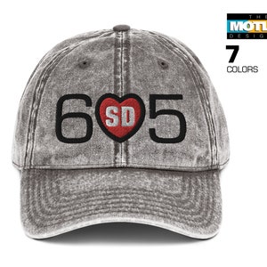 May include: A gray distressed baseball cap with a black embroidered design that says "605" with a red heart containing the letters "SD" in the center.