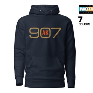 May include: A navy blue hoodie with a gold and orange graphic that says "907 AK".