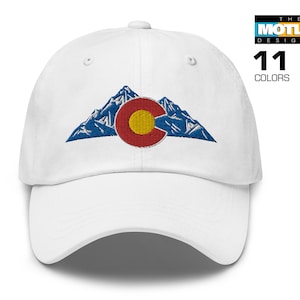 May include: White baseball cap with an embroidered design of the Colorado state flag and mountains. The flag is red, yellow, and blue. The mountains are blue and white.