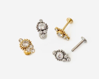 Può includere: Tre diversi stili di gioielli per il corpo con un gruppo di strass trasparenti in un design geometrico. I gioielli sono disponibili in oro e argento.