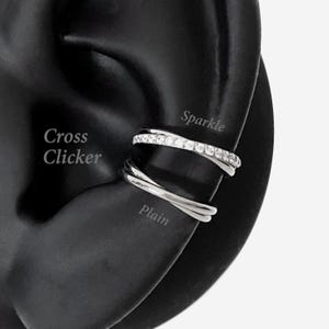 May include: A silver-coloured ear cuff featuring two bands. The upper band is encrusted with small clear stones, labelled as Sparkle. The lower band is a smooth, plain silver-coloured metal, labelled as Plain. The text Cross Clicker is visible nearby.