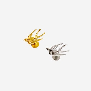 May include: Two stud earrings shaped like swallow birds in flight. One earring is finished in a polished gold tone, while the other is finished in a polished silver tone. Each bird features detailed wing and tail feathers with a post backing.