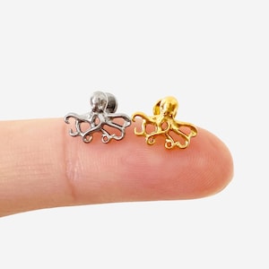 May include: Two small octopus-shaped stud earrings, one in a polished silver tone and one in a bright gold tone. Each earring features a detailed head and multiple curved tentacles extending outward, designed as a pair of metal jewelry pieces.