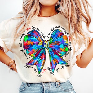 May include: A white t-shirt with a colorful puzzle piece bow and the text "I would not change you for the world." repeated around the bow.