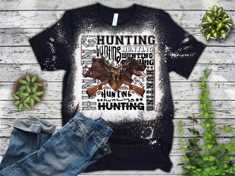 May include: A black t-shirt with a white bleach design featuring a deer, two boar, and rifles. The design includes the word "hunting" repeated multiple times.