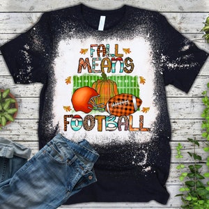 K&ouml;nnte beinhalten: Schwarzes T-Shirt mit einem wei&szlig;en Bleichmittel-Design. Das Design zeigt einen Football, einen K&uuml;rbis und den Text "Fall Means Football".