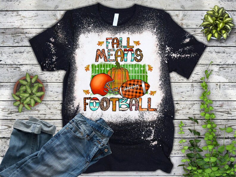 K&ouml;nnte beinhalten: Schwarzes T-Shirt mit einem wei&szlig;en Bleichmittel-Design. Das Design zeigt einen Football, einen K&uuml;rbis und den Text "Fall Means Football".