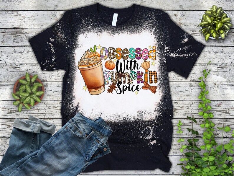 May include: A black t-shirt with a white bleach design. The design features a cup of pumpkin spice latte, pumpkins, and the text "Obsessed with Pumpkin Spice".