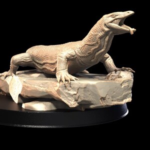 May include: A beige ceramic sculpture of a Komodo dragon with its mouth open, standing on a rocky base. The sculpture is on a black circular base.