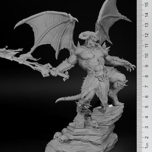 May include: A grey, detailed miniature sculpture of a demon with wings, holding a sword and standing on a rocky base. The demon has horns, a muscular body, and a fierce expression.
