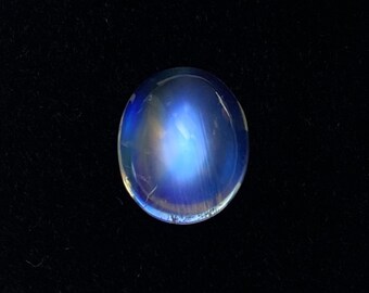 May include: A round, iridescent blue moonstone cabochon with a light blue sheen.