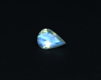May include: A pear-shaped gemstone with a blue and white iridescent sheen. The gemstone is set against a black background.