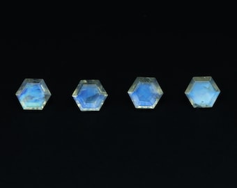 May include: Four iridescent blue hexagonal gemstones on a black background.