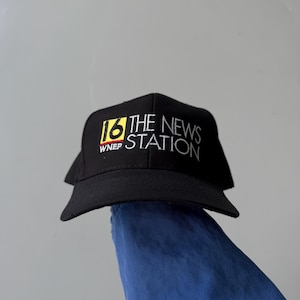 以下が含まれることがあります： 白、黄色、赤で「16 THE NEWS STATION WNEP」の文字が入った黒い野球帽。帽子はカーブしたつばがあり、濃い色の生地で作られています。