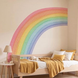 Puede incluir: Dormitorio infantil con una cama de madera clara, ropa de cama mostaza y un gran mural de arcoíris. Una pequeña silla de madera, una mesita auxiliar y una cesta de mimbre con juguetes completan la habitación.