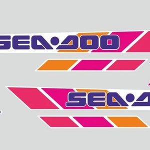 Może przedstawiać: Zestaw naklejek Sea-Doo w kolorze r&oacute;żowym, pomarańczowym i fioletowym z tekstem "Sea-Doo" i "Bombardier".