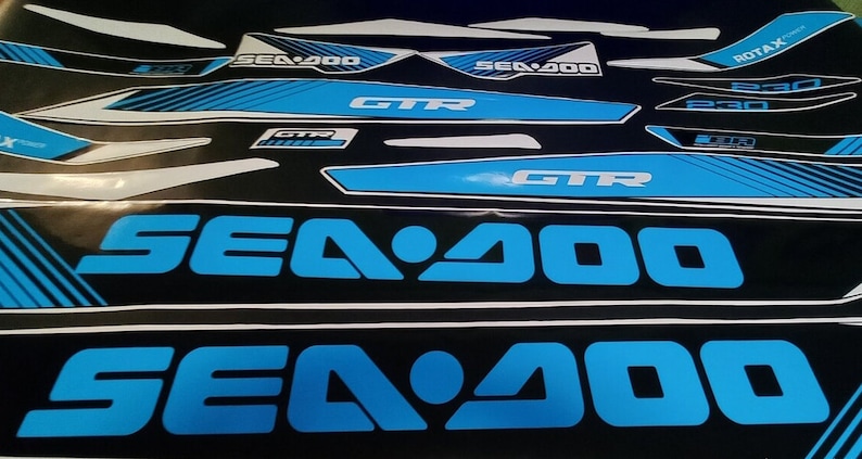 May include: A set of black and blue Sea-Doo GTR decals with the text "Sea-Doo" and "GTR" in a bold, white font. The decals are designed for a Sea-Doo watercraft.