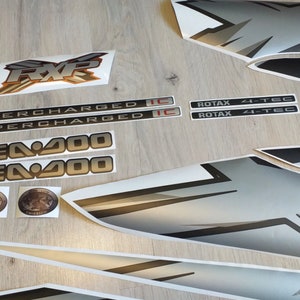 Puede incluir: Un conjunto de calcoman&iacute;as negras y plateadas para una moto acu&aacute;tica Sea-Doo. Las calcoman&iacute;as incluyen las palabras "Sea-Doo", "Supercharged", "RXP", "Rotax" y "4-Tec".