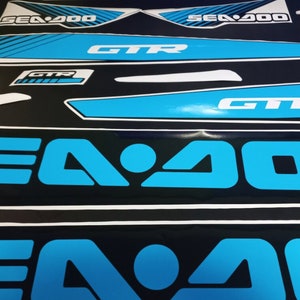 May include: A set of blue and white Sea-Doo GTR decals. The decals feature the Sea-Doo logo and the words "Sea-Doo" and "GTR".