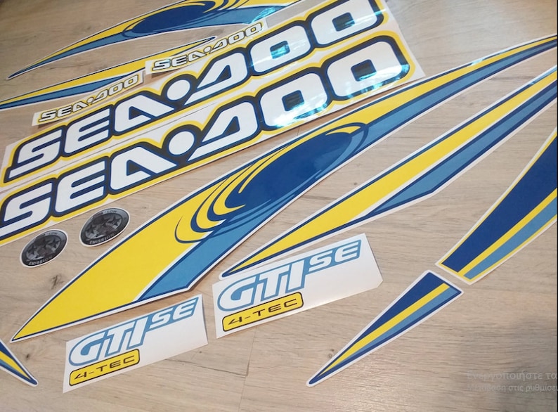 Peut inclure: Un ensemble d'autocollants Sea-Doo bleus et jaunes avec le texte "Sea-Doo" et "4-TEC GTI SE".