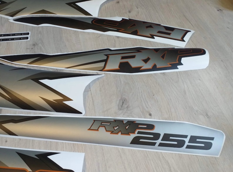 Puede incluir: Un conjunto de calcoman&iacute;as de motocicleta negras y plateadas con el texto "RXP 255" y un dise&ntilde;o gr&aacute;fico estilizado. Las calcoman&iacute;as est&aacute;n sobre un fondo blanco.