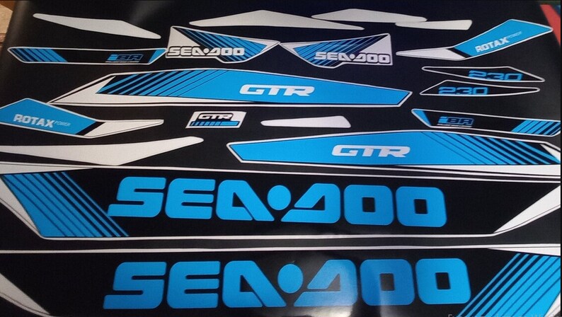 May include: A set of blue and white Sea-Doo GTR 230 decals. The decals feature the Sea-Doo logo, the model name, and the engine size. The decals are designed to be applied to a Sea-Doo watercraft.