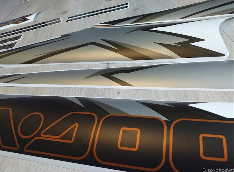 Puede incluir: Un conjunto de calcoman&iacute;as de vinilo en blanco y negro con un dise&ntilde;o gris y naranja. Las calcoman&iacute;as presentan la palabra "400" en una fuente negrita y estilizada.