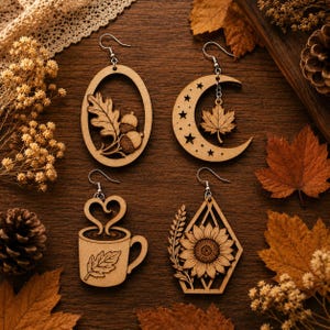 May include: Four laser-cut wooden earrings with silver-toned hooks. One oval frame features an oak leaf and acorns, a crescent moon with stars and a maple leaf, a coffee mug with heart-shaped steam, and a geometric frame with a sunflower.